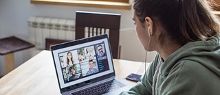 Laua taga istub naine, kellel on kõrvaklapid peas. Ta jälgib veebi teel videokonverentsi ja teeb vihikusse märkmeid. Tema kõrval on lahtine õpik, marker ja nutitelefon. 