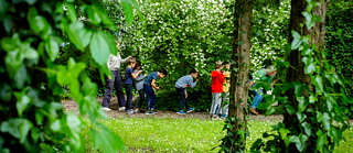 Kinder spazieren im Garten und riechen an Holdunderblüten am Baum