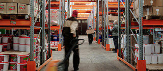 Auf dem Foto sieht man einen Arbeiter in einer riesigen Lagerhalle