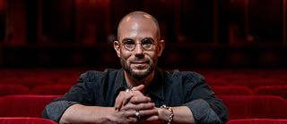 Clément Viktorovitch lehnt sich auf einen roten Sessel vor