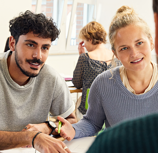 Gespräch im Klassenraum, 3 Personen unterhalten sich, 1 Person ist von hinten zu sehen