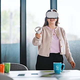 Eine Frau in einem Büro, die ein Virtual-Reality-Headset trägt und sich auf ein immersives digitales Erlebnis einlässt.