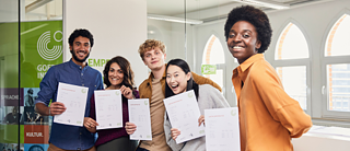 Diverse group of students smiling, holding Goethe-Institut German language course certificates.