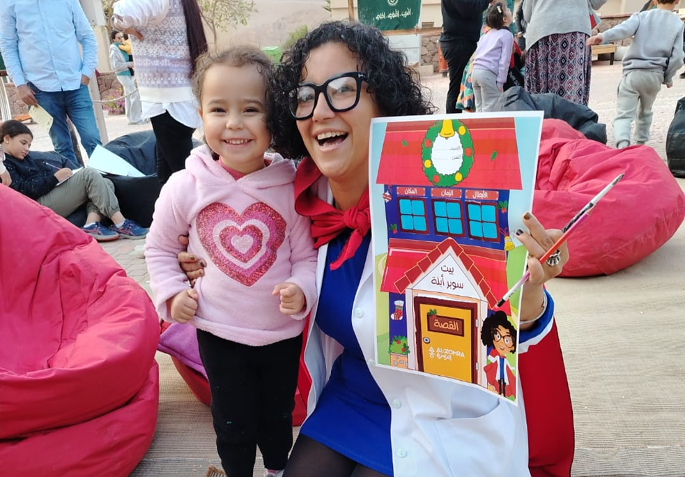 سيدة تقف مع عدد من التلاميذ في ساحة مفتوحة.