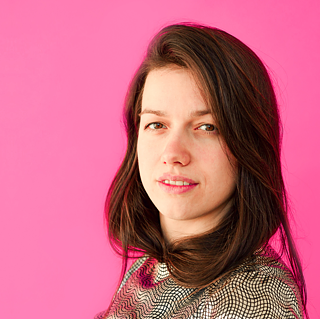 Alica Minar im Portrait vor einer pinken Wand.