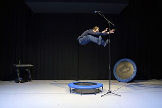 Felix Baumann springt auf einem Trampolin in Richtung eines Mikrofons, das über ihm befestigt wurde.