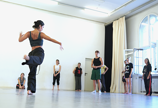 Man sieht Beatriz Silva Aranda, die weiteren Teilnehmer*innen ihres Workshops "Movement Invitations" eine Bewegung demonstriert.