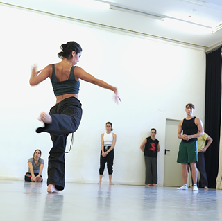 Man sieht Beatriz Silva Aranda, die weiteren Teilnehmer*innen ihres Workshops "Movement Invitations" eine Bewegung demonstriert.