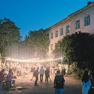 Vielen Menschen draußen auf einem Hof mit Lampen