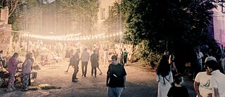 Vielen Menschen draußen auf einem Hof mit Lampen