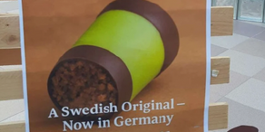 Werbeplakat, auf dem eine schwedische Punschrolle in grün und braun abgebildet ist.