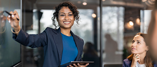A woman gives a presentation to her colleagues in front of a board.