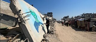 فنان يرسم على قطعة كبيرة من أنقاض منزل مدمر.