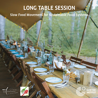 Langer Holztisch mit Tellern, Gläsern und Trockenblumen für eine Slow-Food-Veranstaltung im Freien.