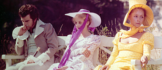 Auf einer Bank sitzen nebeneinander und mit voneinander abgewandten Gesichtern v.l.n.r. ein junger Mann, Tochter Lotte und Charlotte Kestner.