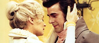 A woman takes a man's face between her hands.