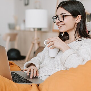 Woman relaxing in a comfortable chair with a coffee mug while participating in an online German Coffee Break Conversation Group with Goethe-Institut USA.