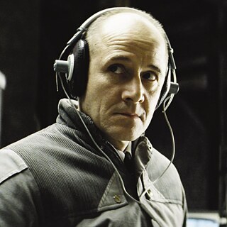 Das Foto zeigt den Hauptdarsteller mit einem Abhörgerät auf den Ohren.