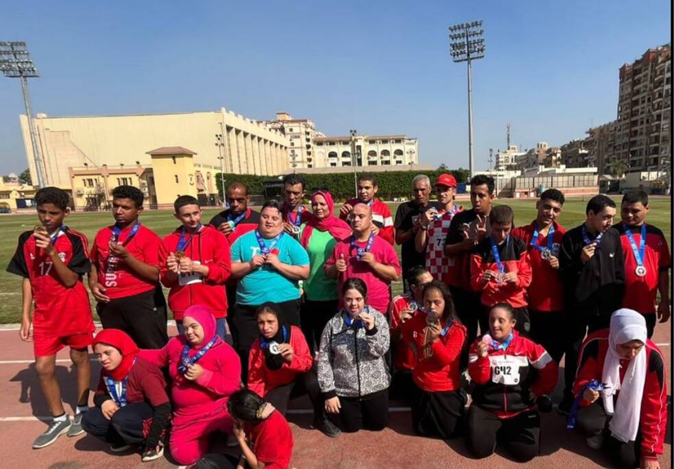 Viele Kinder, Jungen und Mädchen, die Mehrheit trägt rote T-shirts, posieren für ein Gruppenfoto. Alle haben Medaillen um den Hals.