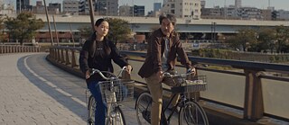 Still from Perfect Days by Wim Wenders - two people on bicycles 