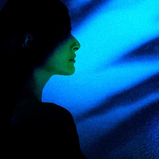 O perfil de uma mulher é iluminado por uma luz azul