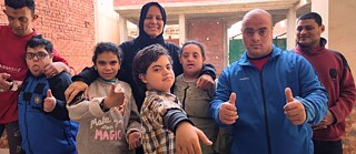 Eine Gruppe von Kindern, Teenagern und einigen Erwachsenen schaut in die Kamera und zeigt den Daumen nach oben.