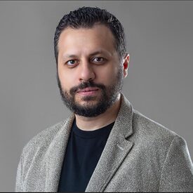 Black and white portrait of a bearded man looking directly into the camera.
