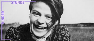 Sophie Scholl als junge Erwachsene, lachend, mit geblümtem Kleid vor Wiese, schwarz-weiß Aufnahme ohne Datum.