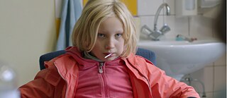 „Foto eines Mädchens, das auf einem Stuhl sitzt.