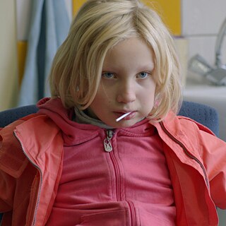 Foto eines Mädchens, das auf einem Stuhl sitzt.