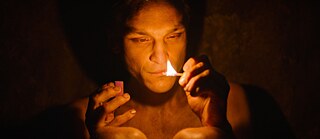 „Ein Mann im Vordergrund zündet ein Streichholz an