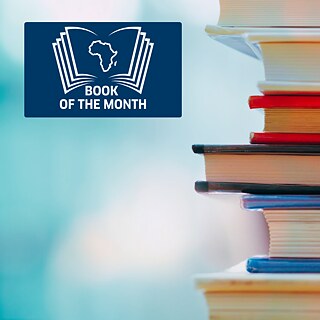 An open book in front of a book shelf. The book of the Month logo is right above that open book. 