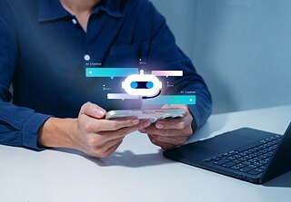 شخص يرتدي قميصًا أزرق يحمل هاتفًا محمولًا، حيث تظهر المحادثات بشكل خيالي وهي معلقة في الهواء.
