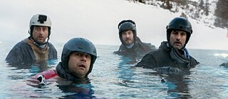 Still Frame from the Netflix Germany Series "Dudes": the four "Dudes" David Rott; Moritz Führmann; Serkan Kaya; Tom Beck are standing in full ski gear deep to their chests in a lake in a winter landscape.