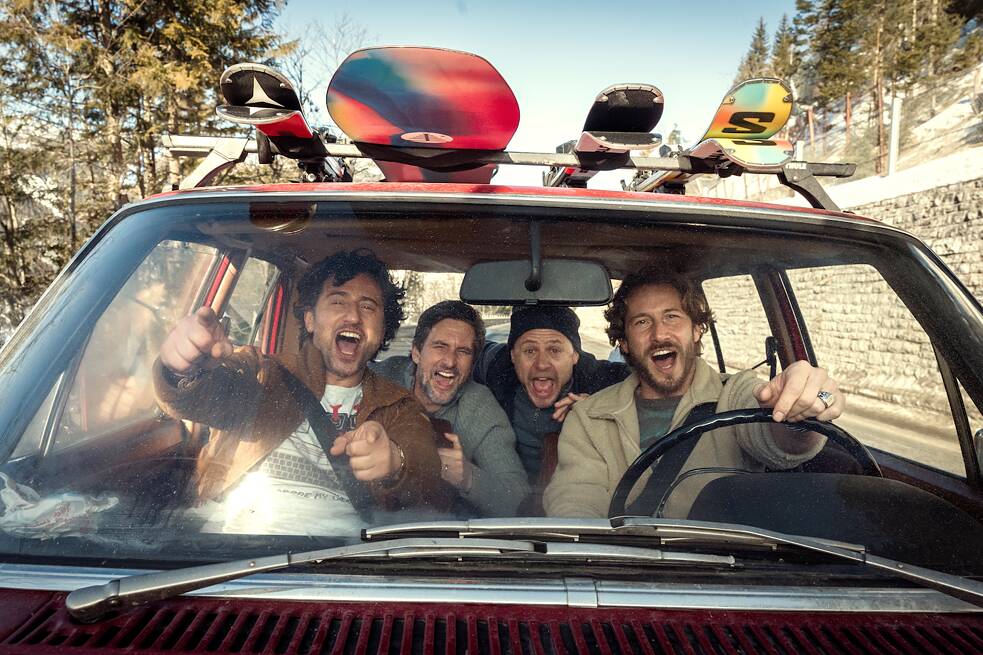 Still Frame from the Netflix Germany Series "Dudes": the four "Dudes" David Rott; Moritz Führmann; Serkan Kaya; Tom Beck joyously laughing in a car with ski gear on the roof rack