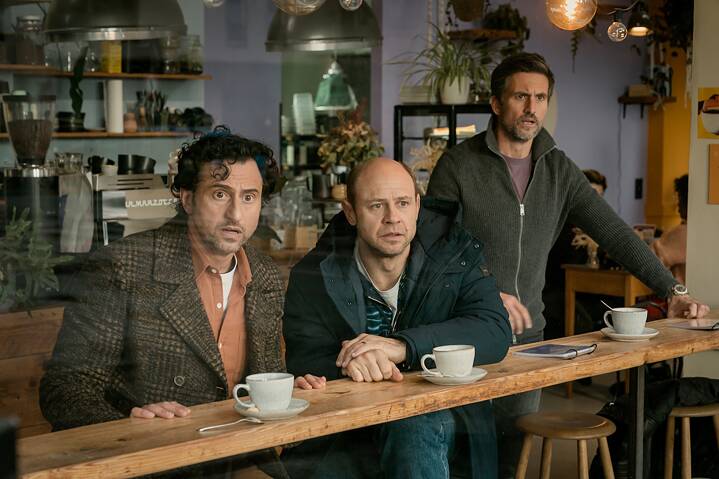 Still Frame from the Netflix Germany Series "Dudes": Moritz Führmann; Serkan Kaya; Tom Beck staring in diesbelief through a window from inside a coffee shop.