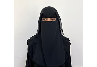 صورة لامرأة ترتدي نقابًا أسود، تنظر بعيدًا عن الكاميرا.