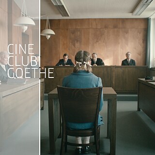 Ein Mädchen mit geflochtenen Zöpfen sitzt in einem Gerichtssaal im Zeugenstand. Sie ist nur von hinten zu sehen. Sie wird von älteren Richtern kritisch angeschaut.