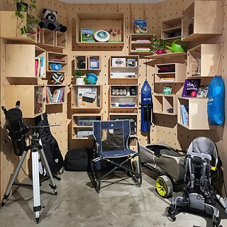 Drevená policová stena s množstvom priehradiek plných vecí na zapožičanie: knihy, hry, rastliny, ďalekohľad, kempingová stolička, kočík, batoh a športové predmety. Usporiadaný priestor „Knižnice vecí“.