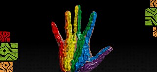 Hand raised against a black background, coated in thick rainbow-colored paint from red to purple.