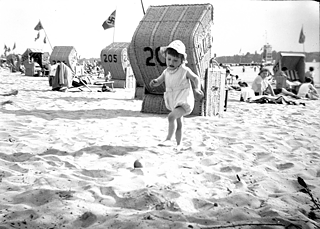 A child play on the Wannsee beach, a Nazi flag flies in the background