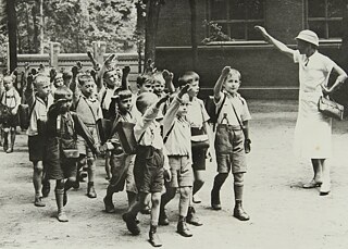 An elementary school class and their teacher perform the compulsory Nazi salute in a schoolyard in Germany, circa 1933.