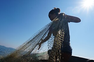 En la Bahía de Guanabara, la pescadora Aline Luz lanza su red al mar, pero ya casi no pesca nada —una señal clara de que la pesca industrial y las empresas petroleras están desequilibrando las aguas y, con ello, desplazando cada vez más los modos de vida tradicionales.