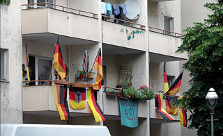 German flags are hanging from the walls and balconies of houses. 