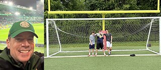 Portrait of Ernie Goodwin, President of FC Somers  (left), high school Fußballspieler Shane Carroll, James Brinn (holding a soccer ball) and Joe Bojaj in front of the goal at the high school sports field.