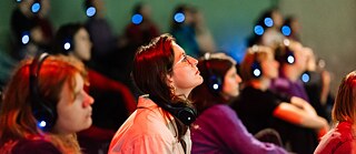 young people with headphones watching a film