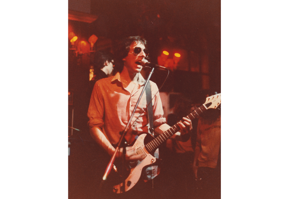 A young man plays a guitar and sings