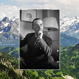 Ein Bild von Autor Thomas Mann der interessiert dreinschaut und sich die Hand an das Kinn hält. Dahinter ist eine schweizer Alpenlandschaft.