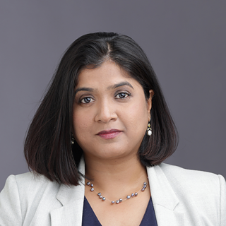 This image is a professional studio headshot featuring a single person centered in the frame against a smooth gray gradient background.
