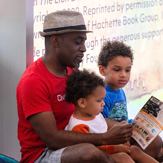An adult reading a book to two children